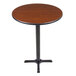 A Lancaster Table & Seating round table with a black metal base and a reversible wooden top.