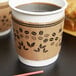 A brown paper coffee cup sleeve with a coffee cup inside.