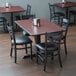 A table and chairs in a restaurant dining area with a black chair with a black cushion.