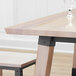 A Lancaster Table & Seating live edge wooden table top with a glass on it.