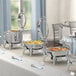 An outdoor buffet table with Acopa Voyage stainless steel chafers on stands.