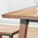 A Lancaster Table & Seating live edge wood table top with a glass on it.