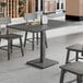 A rectangular solid wood table with a live edge and slate gray finish, paired with matching chairs in a modern dining setting.