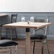 A Lancaster Table & Seating solid wood live edge table with an antique white finish and two chairs.