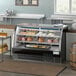 An Avantco black curved glass refrigerated deli case with meat and cheese on display.