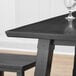 A Lancaster Table & Seating solid wood table top with a wine glass on it.