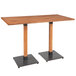 A Lancaster Table & Seating wooden bar table with two black metal legs.