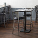 A Lancaster Table & Seating live edge bar height table with an antique slate gray finish on a table in a restaurant dining area.