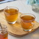 A wooden tray with two cups of Numi Organic Jasmine Pearls green tea.