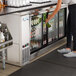 A woman putting a bottle of beer in an Avantco back bar cooler.