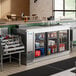 An Avantco stainless steel back bar refrigerator with bottles on metal shelves.