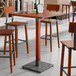 A Lancaster Table & Seating live edge bar height table with a rustic mahogany surface.