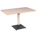 A Lancaster Table & Seating solid wood dining table with a metal base and black legs.