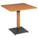 A Lancaster Table & Seating square wooden table with a metal base.