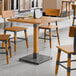 A Lancaster Table & Seating live edge wood table with a honey maple finish and chairs in a restaurant.
