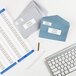 A white desk with a keyboard and a mouse and Avery glossy white address labels on several envelopes.