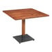 A Lancaster Table & Seating solid wood square table with a black metal base.