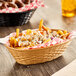 A tan plastic oval serving basket filled with french fries and chicken wings on a table in a family-style restaurant.