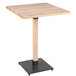 A Lancaster Table & Seating square wooden bar height table with a black metal base.