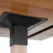 A black metal support plate on a Lancaster Table & Seating wood table.