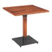 A Lancaster Table & Seating square wooden table with a metal base.