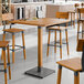 A Lancaster Table & Seating industrial wooden bar height table with stools.