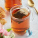 A glass mug with a Numi Organic Aged Earl Grey Tea bag in it.