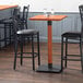 A Lancaster Table & Seating bar height table base with chairs around it in a restaurant dining area.