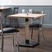 A Lancaster Table & Seating live edge wood table with Antique White Wash finish and two chairs on a table in a restaurant dining area.