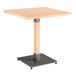 A Lancaster Table & Seating square table with a metal base and wooden top.