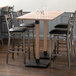 A Lancaster Table & Seating solid wood live edge bar height table with an antique white wash finish and chairs around it.