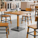 A Lancaster Table & Seating wooden table with metal legs and chairs in a room.
