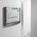 A Durable gray interior wall click sign holder with a sign on a wall.