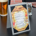 A Menu Solutions Alumitique table tent on a table with a menu.