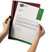 A person's arm holding a clear and maroon Durable DuraClip report cover with a document inside.