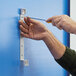 A person using a screwdriver to install a Durable 5 panel wall-mount reference system.