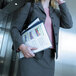 A woman in a suit holding a Durable navy vinyl report cover with a file and a phone.