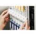 A person's hands holding a key to a silver brushed aluminum key cabinet.