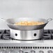 A Town hand hammered Cantonese wok on a stove with food in it.