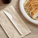 A plate of food with a white EcoChoice compostable plastic knife on a table.