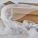 A box with Sealed Air bubble wrap and wine glasses with bubble wrap on a wooden table.