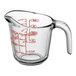 An Anchor Hocking clear glass measuring cup with a red handle and red measurement markings.