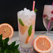 A Libbey Tritan plastic stackable cooler glass of water with ice, orange slices, and leaves.