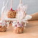 A group of caramel apples wrapped in clear plastic.