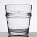 A close up of a Libbey Tritan plastic stackable rocks glass filled with a clear liquid on a table.