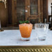 a glass of orange liquid on a marble table