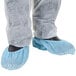 A person wearing blue Cordova shoe covers over shoes.