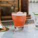 Two Arcoroc stackable rocks glasses filled with pink cocktails on a bar counter.