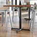 A Lancaster Table & Seating black cast iron counter height table base with a table and stools.