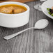 A bowl of soup with a Oneida Baguette stainless steel bouillon spoon on a table.